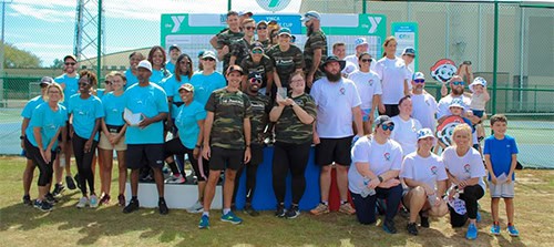 Group of college students and staff celebrating victory at YMCA sports event.