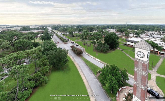 Aerial view of Pensacola State College campus with clock tower, lush greenery, and scenic pathways f.