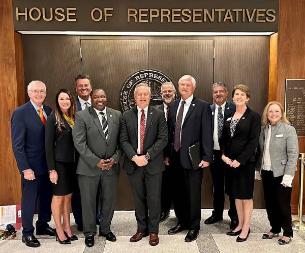 Group of diverse professionals advocating for Florida College System in government building.