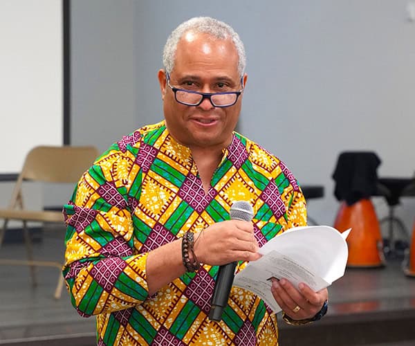 Black History Month event at Pensacola State College with speaker in vibrant African print shirt.