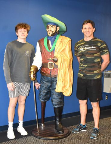Pirate mascot standing with two students in casual attire at Pensacola State College.