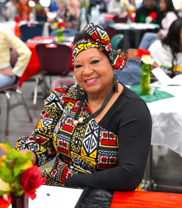 Diverse woman in vibrant African print attire at Black History Month event.