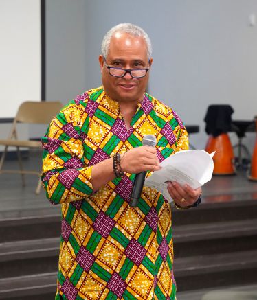 Diverse speaker at PSC honors Black History Month with cultural attire and presentation.