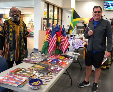 Diverse individuals celebrating Black History Month at PSC with cultural flags and educational displ.