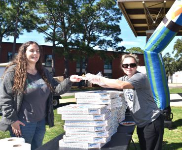 Food donation event at Pensacola State College campus with students distributing supplies.