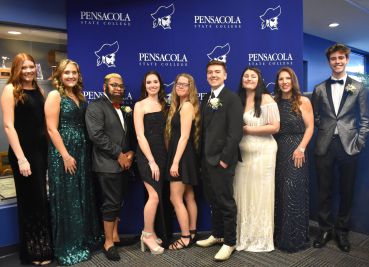 Students dressed in formal gowns and suits at Pensacola State College celebration.