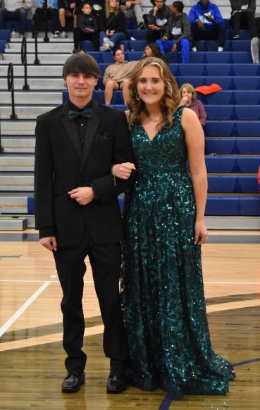 Young man and woman dressed in formal attire at college event.