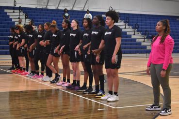 Women's basketball team preparing for game in gymnasium, showcasing team unity and athleticism.