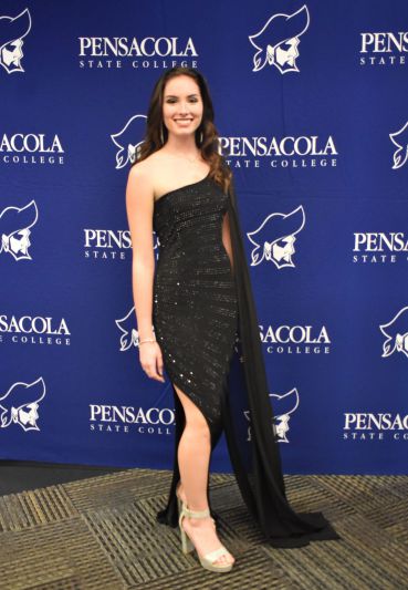Graduation gown and elegant dress worn by student at Pensacola State College ceremony.