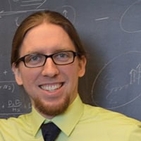 Student in honors program smiling in classroom with chalkboard background.