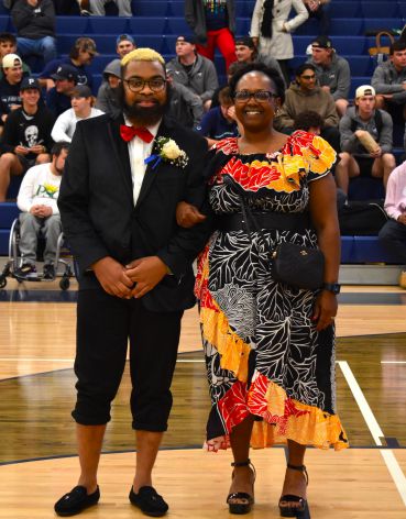 Diverse students celebrating graduation in gymnasium.