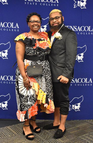 Smiling woman and man in formal attire at college event.