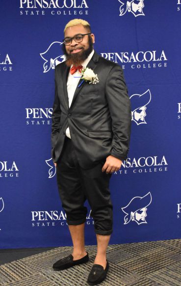 Smiling graduate in formal attire at Pensacola State College graduation event.