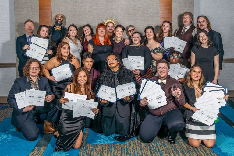 Group of diverse students holding certificates at the Pensacola ADDY awards ceremony, celebrating th.