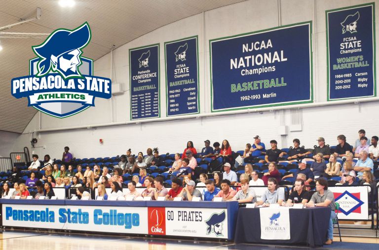Pensacola State College basketball team with banners celebrating NJCAA national championships.