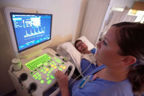 Ultrasound technician conducting medical imaging for patient diagnosis.
