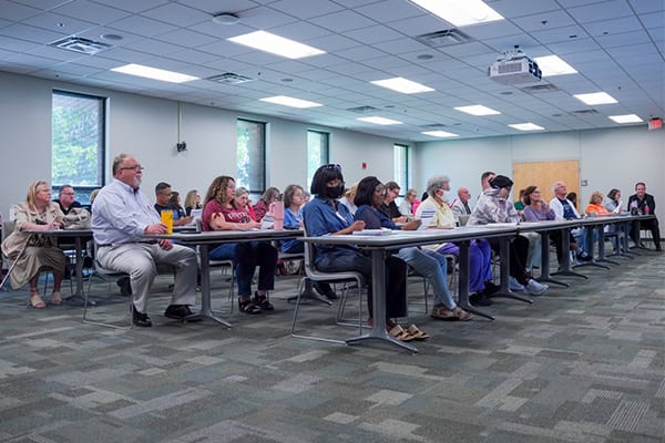 Higher education professionals discussing state benefits at Pensacola State College meeting.