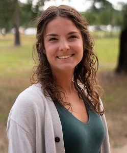 College student smiling outdoors at Pensacola State College campus.
