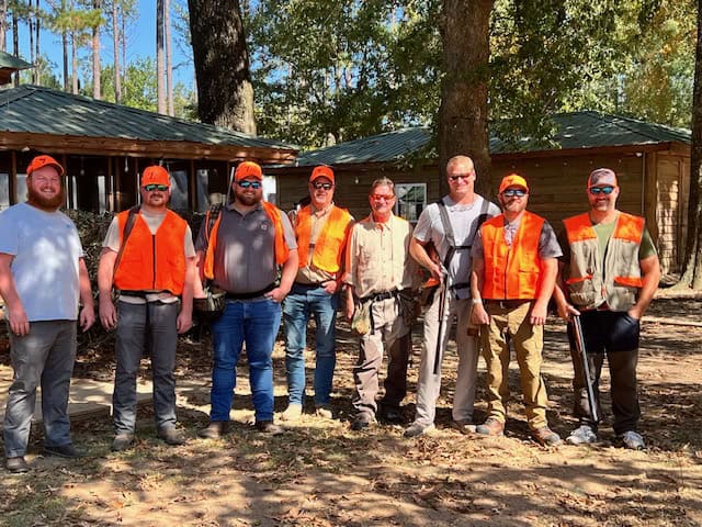 Outdoor team activity with students and staff in safety vests at Pensacola State College campus.