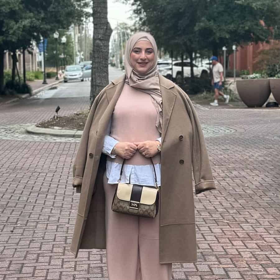 Woman in modest attire celebrating Fall 2024 graduation at Pensacola State College campus.