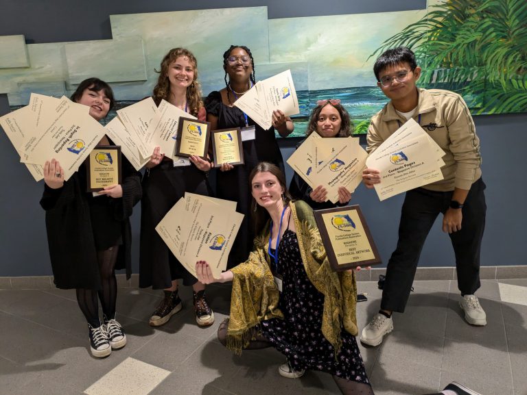 Students holding certificates and plaques at an academic awards ceremony.