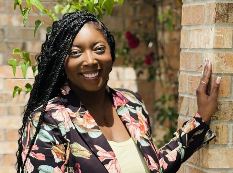 Diverse African American woman smiling outdoors, standing by brick wall, celebrating higher educatio.
