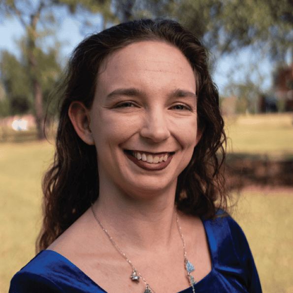 Portrait of a smiling female faculty member receiving the Teaching Excellence Award outdoors.