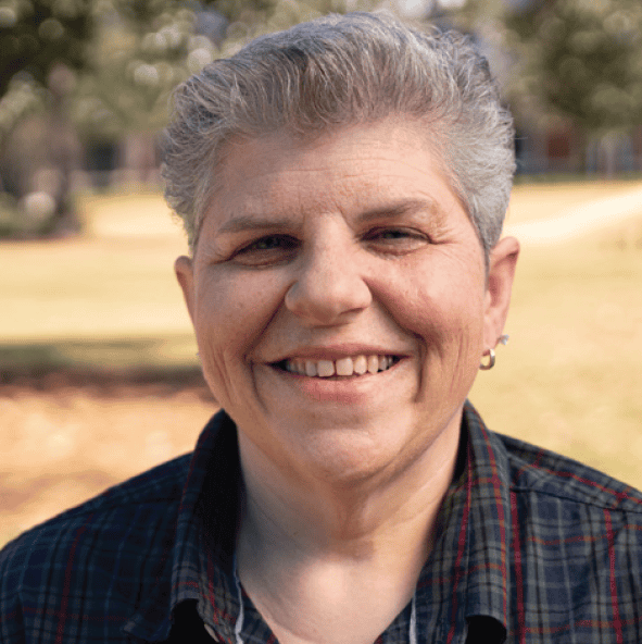 Smiling woman outdoors, celebrating teaching excellence award at Pensacola State College campus.