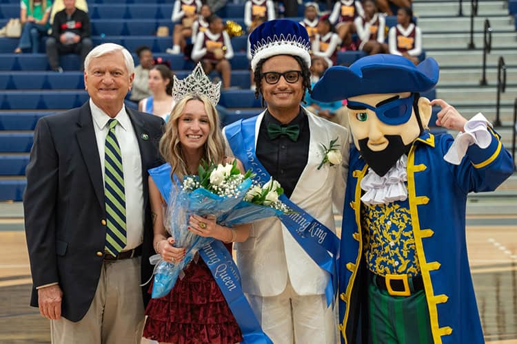 High school homecoming celebration with students, faculty, and mascot at Pensacola State College gym.